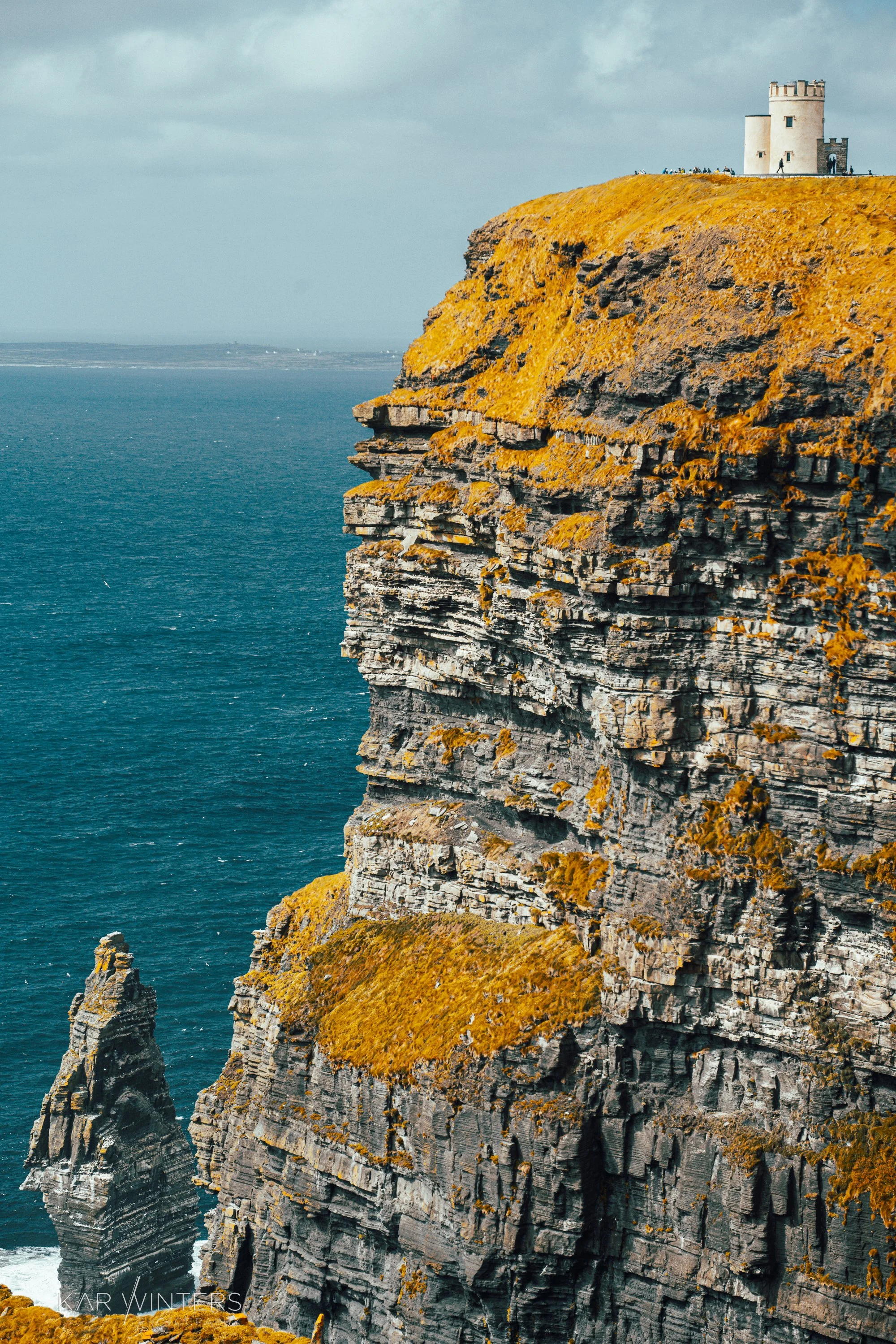 Cliffside with a historical tower on top, overlooking the ocean.