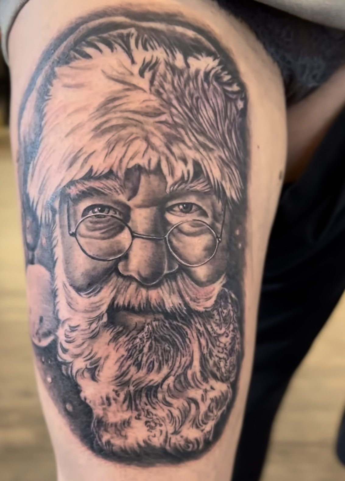 Tattoo of a Santa Claus face with glasses and a hat on skin