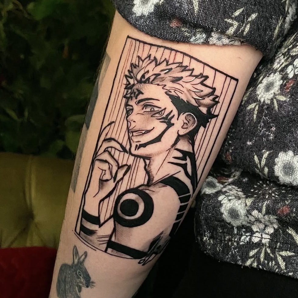 Black and white tattoo of an anime character with spiky hair and tribal markings, positioned on an arm.