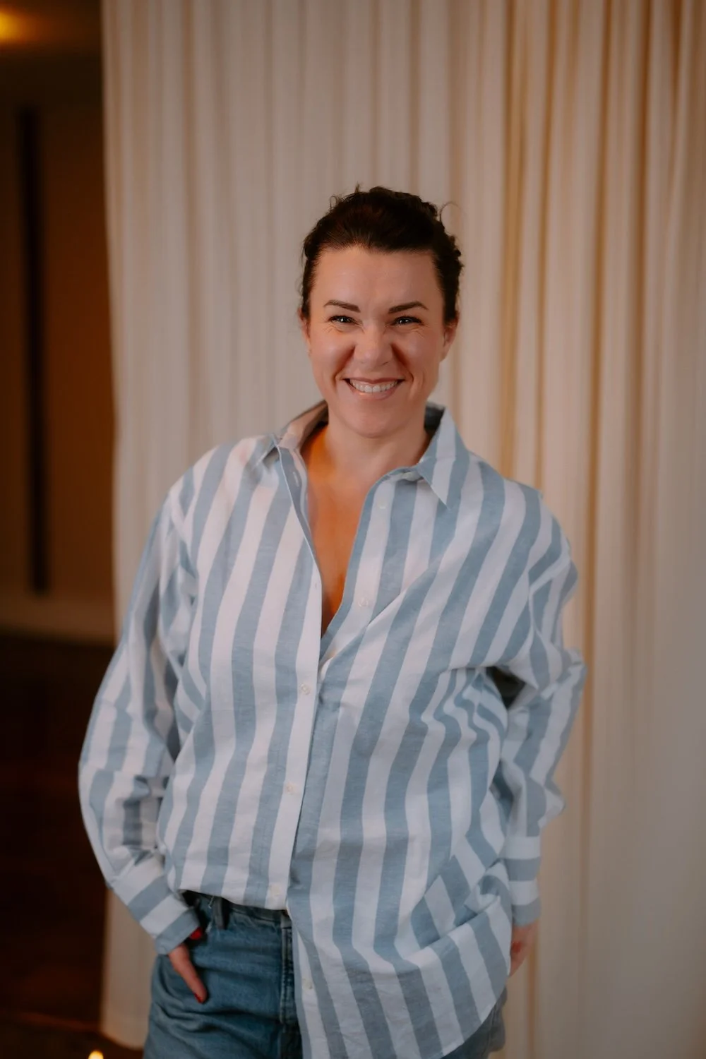 Jodie wearing a striped shirt and jeans smiling