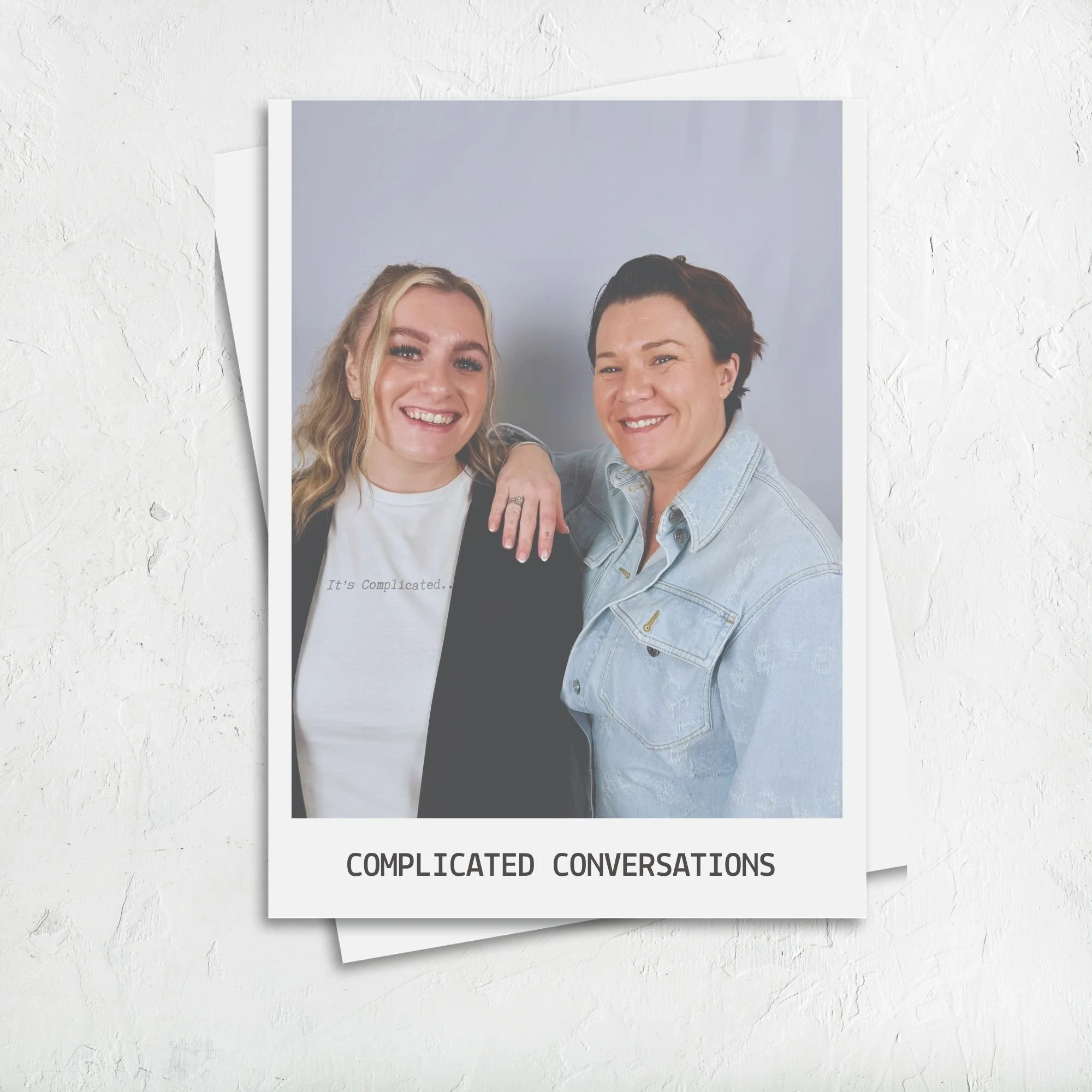 two women standing side by side one wearing a white t-shirt one wearing a denim shirt