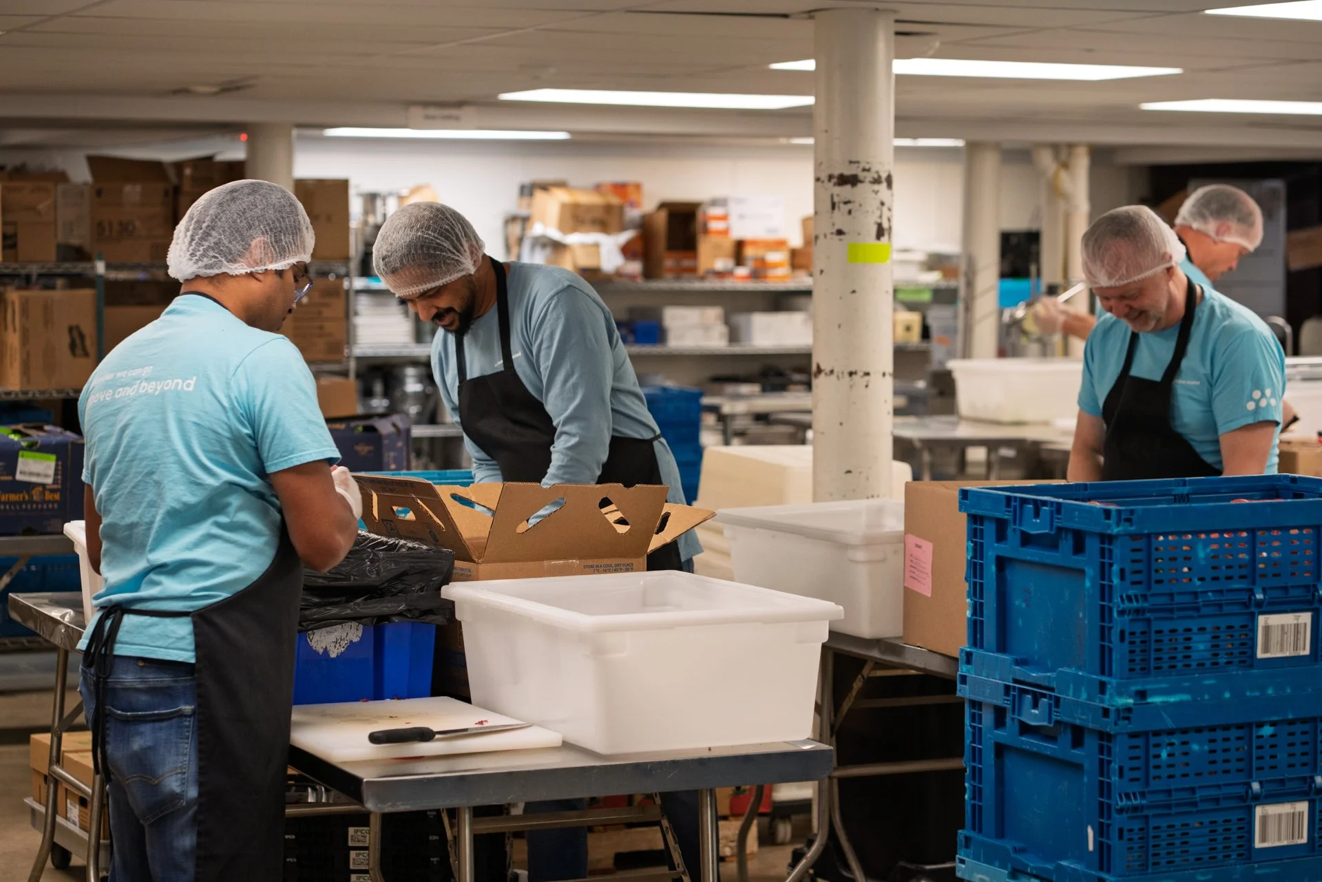 Volunteers in light blue shirts smile as they prepare food for La Soupe in effort to reduce food waste