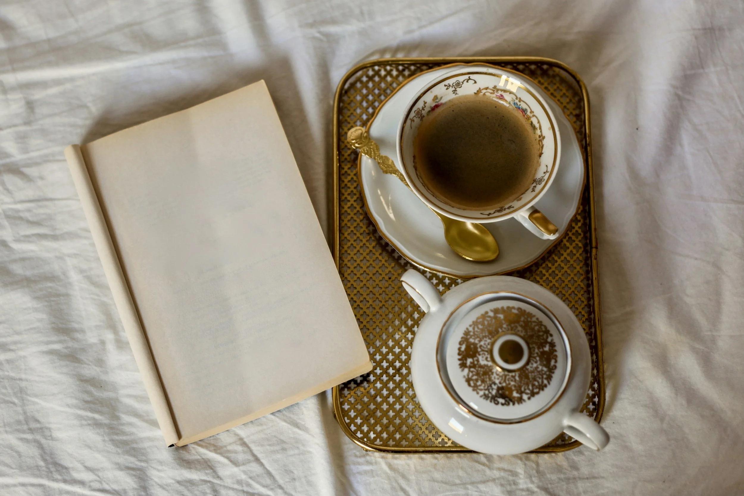Warm morning scene with a blank notebook, teapot, and mug resting on a tray in soft natural light.