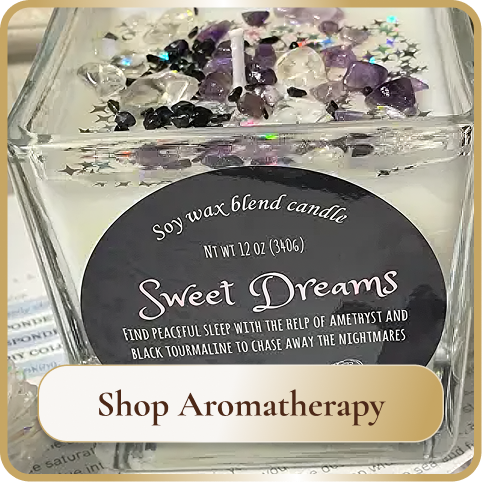 A glass candle holder with a soy wax blend candle labeled 'Sweet Dreams' and decorated with star-shaped and gemstone-like embellishments on top, with a