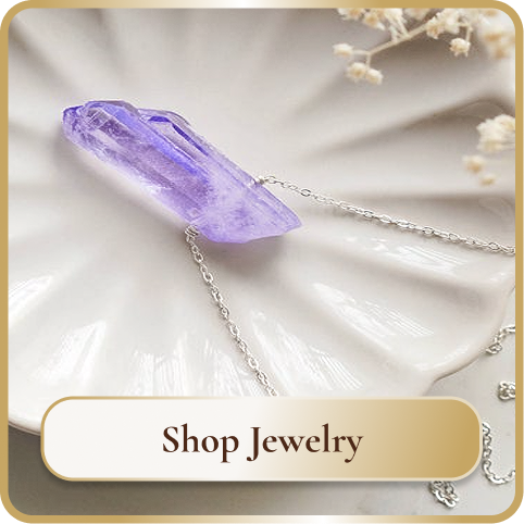 Purple crystal necklace with silver chain on a white textured background with small white flowers and a gold-bordered "Shop Jewelry" button.