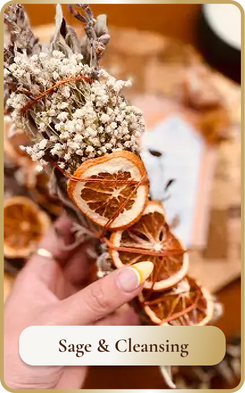 Hand holding dried citrus slices, sage, and white flowers, with text 'Sage & Cleansing'.