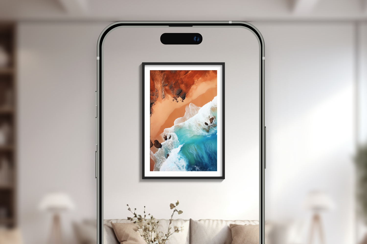 Smartphone capturing a photo of a framed aerial landscape painting of a beach with turquoise waves and rocky shoreline, hanging on a white wall in a modern living room.