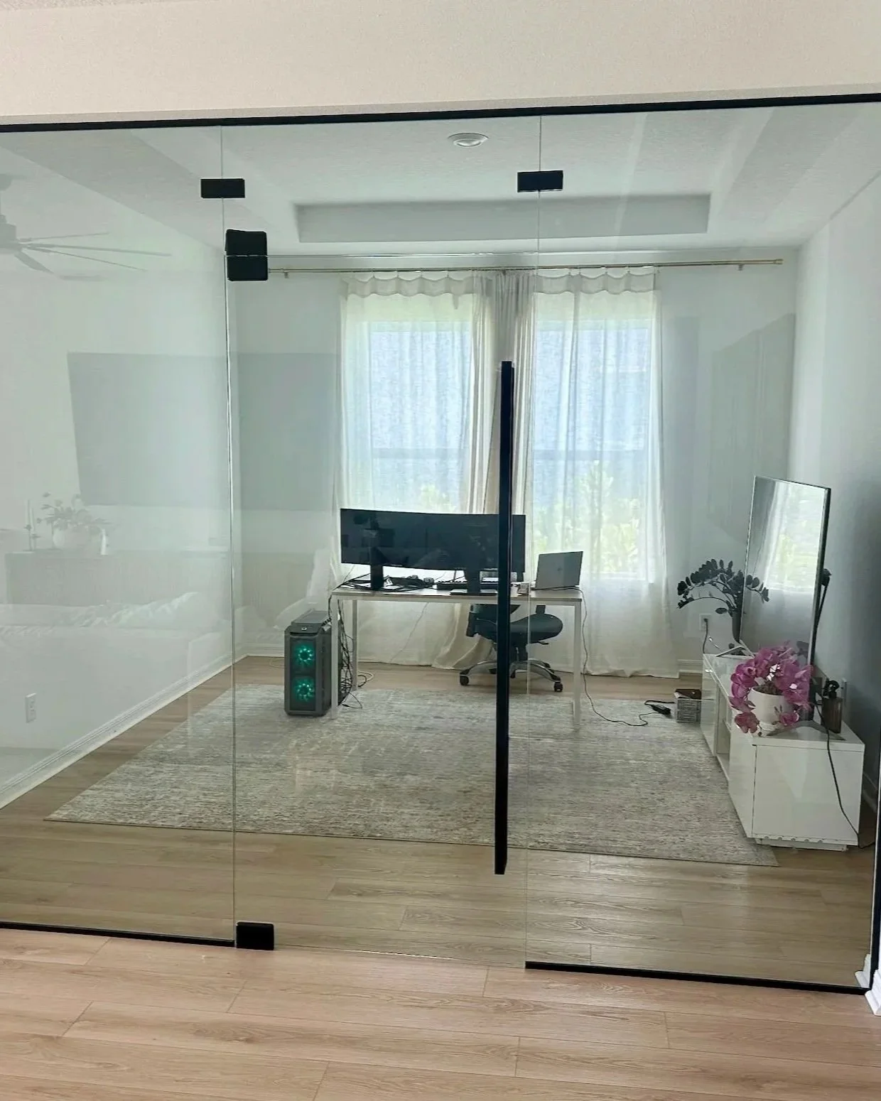 A modern home office viewed through a custom glass enclourse