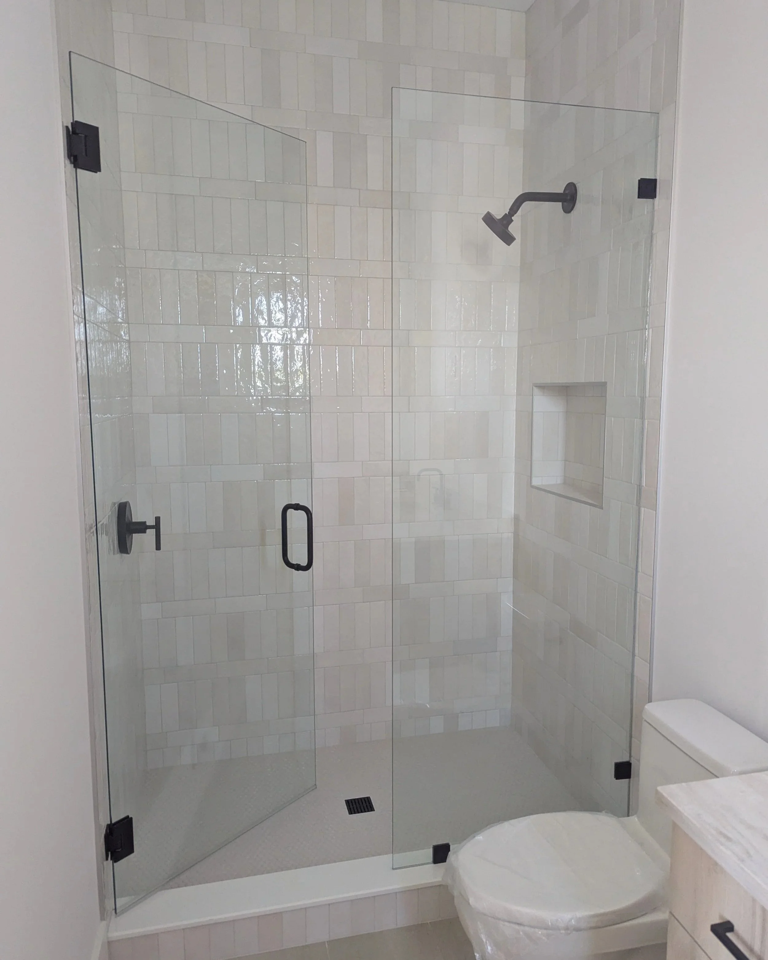 Bathroom with a custom glass shower enclosure with clear tempered glass and matte black shower hardware.