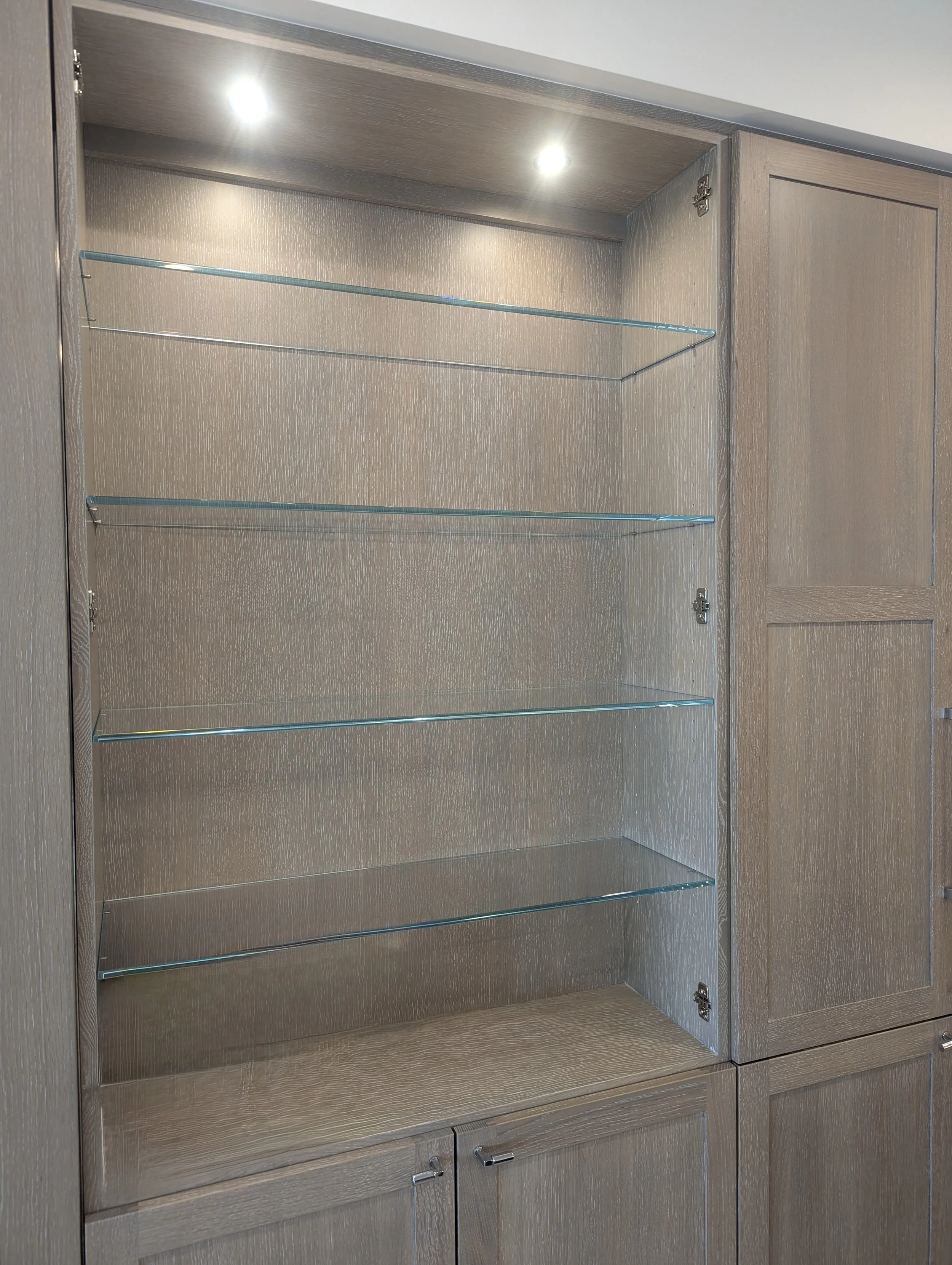 Custom wooden cabinet with low iron glass shelves and built-in lighting.