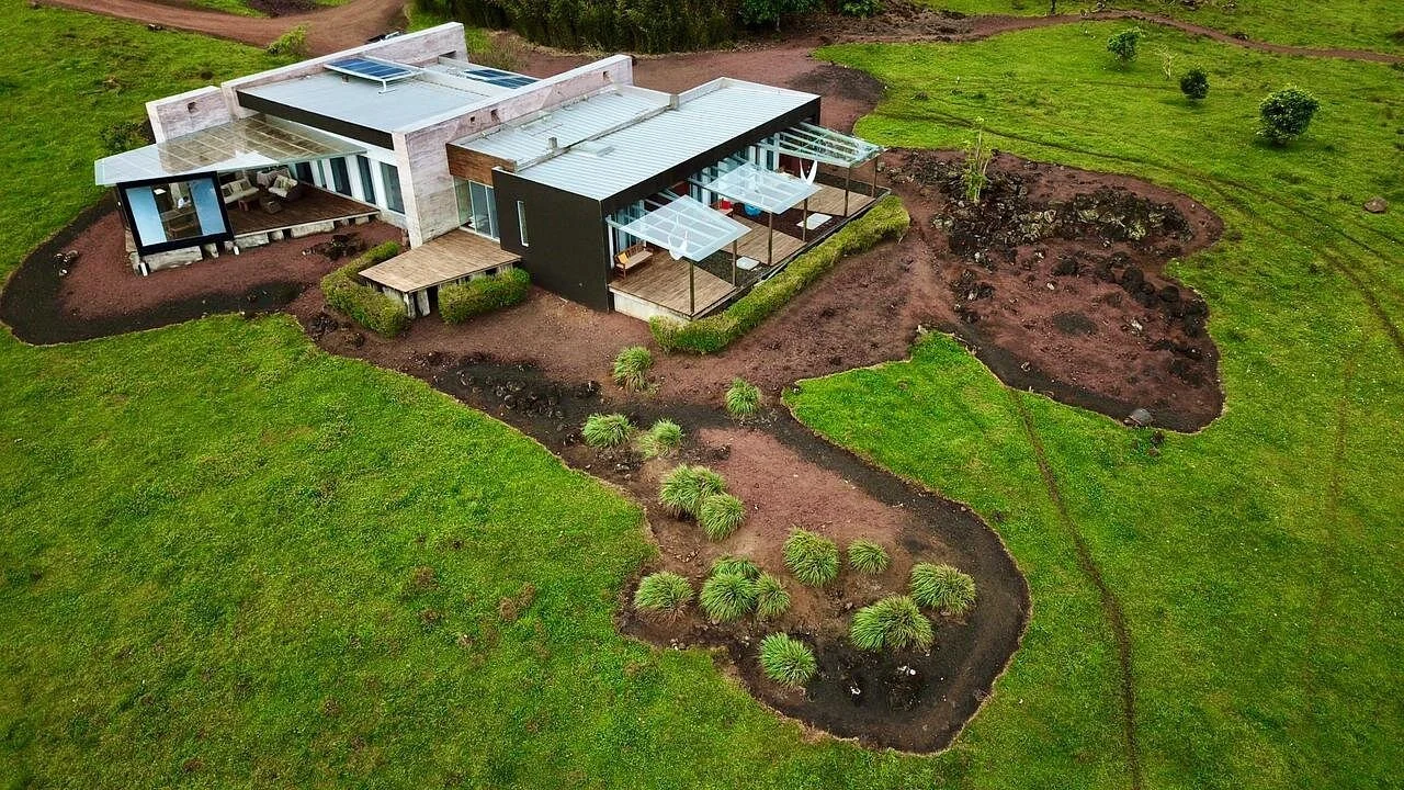 Aerial view of a modern house surrounded by green grass and landscaped garden.