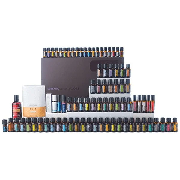 A collection of dōTERRA essential oils bottles arranged in rows and stacks with a storage box in the background.