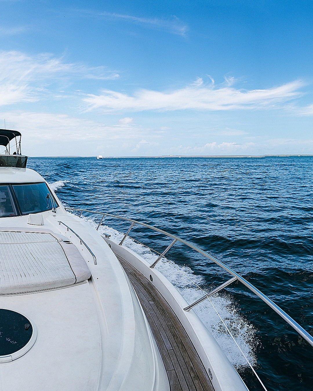 View from a boat on the water with a bright blue sky and some clouds.