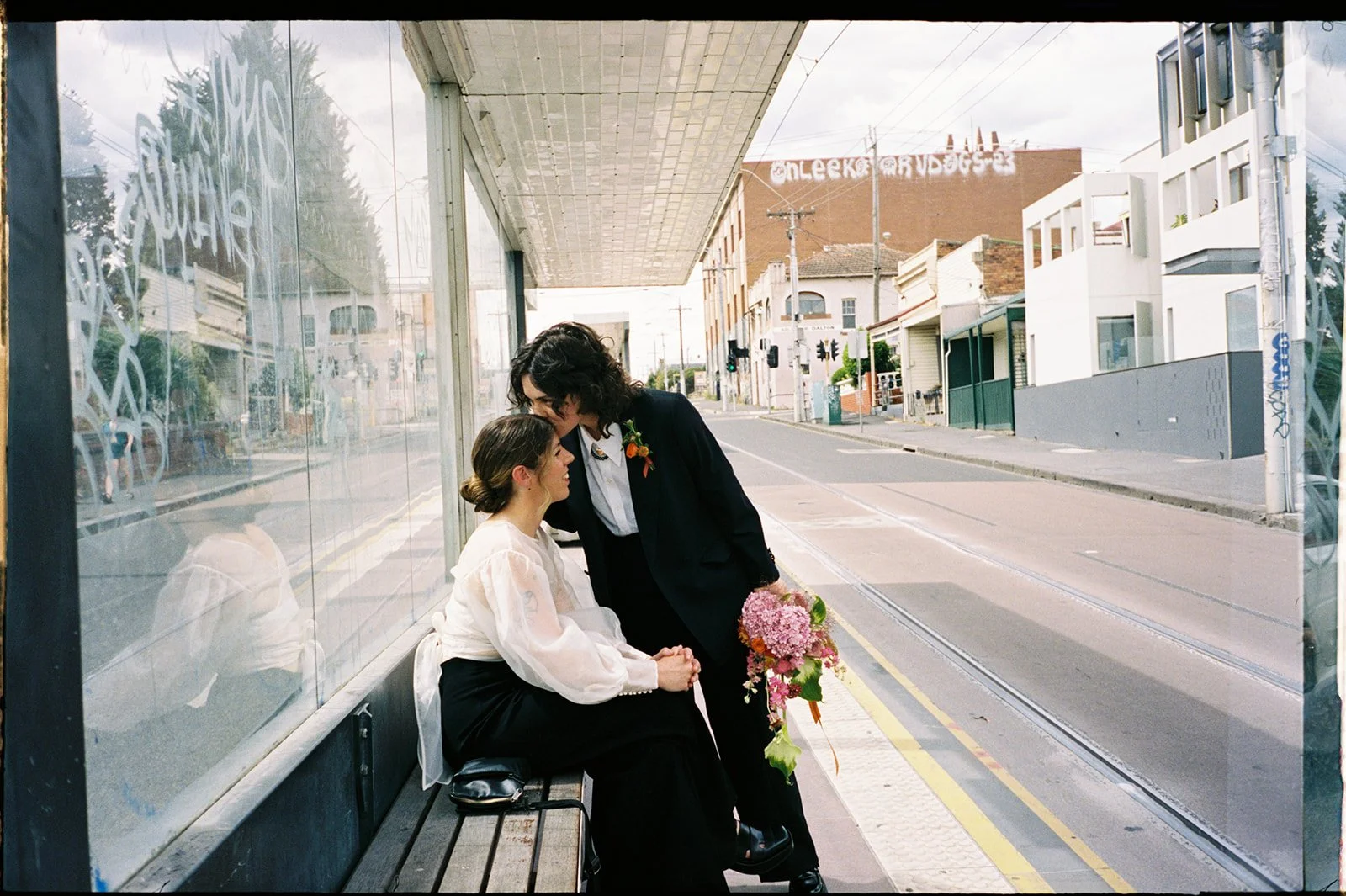 Couple embracing at a Melbourne tram stop during an intimate city micro wedding in Melbourne.