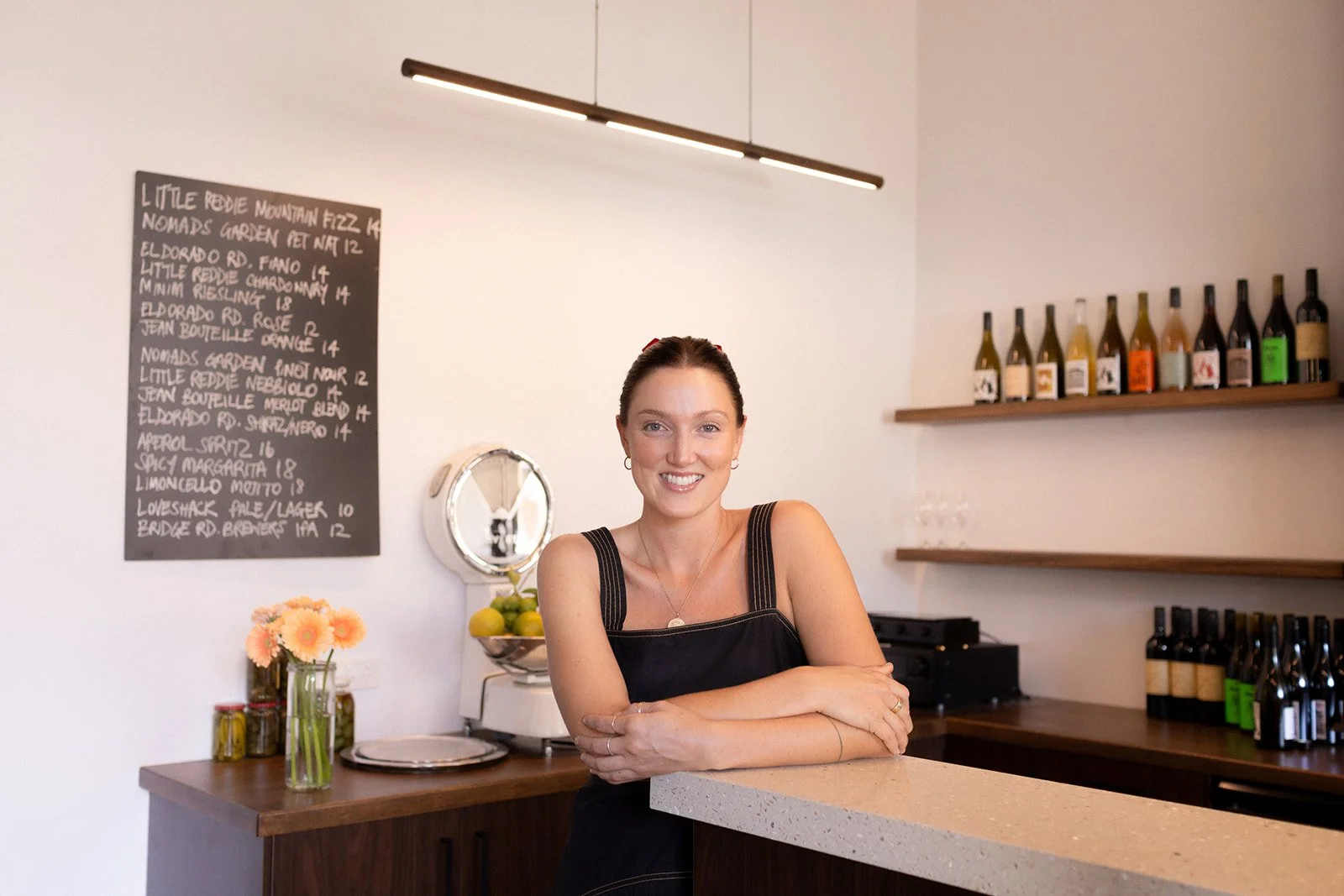 headshot of a business owner in Castlemaine, stood in their restaurant with wine and flowers in the background.