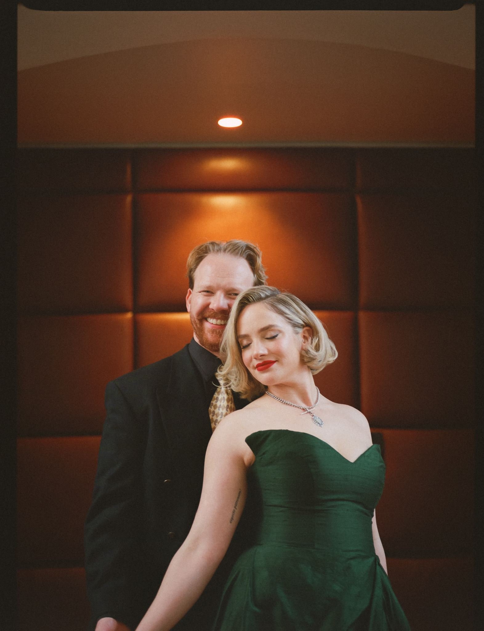 Annabelle and Dom posing together at their winter wedding at Old Palm Liquor in Brunswick East, Melbourne. Annabelle wears a handmade green wedding dress.
