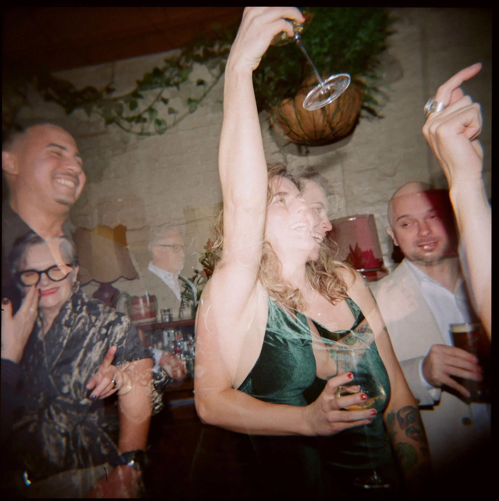 Candid film photograph of wedding guests dancing and celebrating during an evening reception.