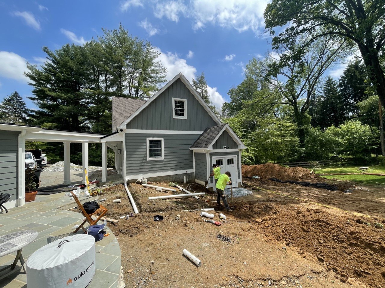 Backyard construction site with workers, house, and trees