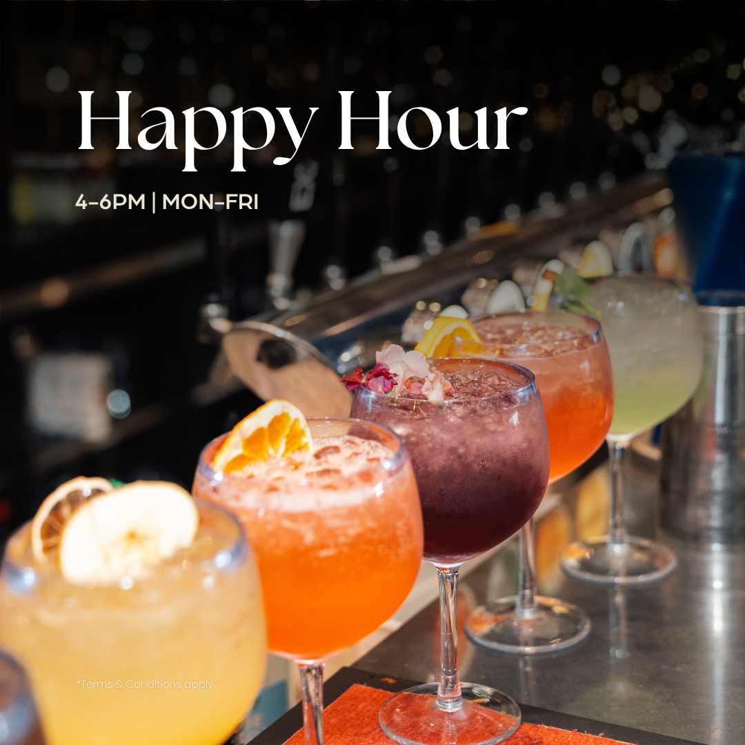Assorted cocktails and beverages on a wooden table with various garnishes such as mint, lemon, and cucumber. Text overlay announces 'Happy Hour, $2 off all drinks! 4PM - 6PM.'
