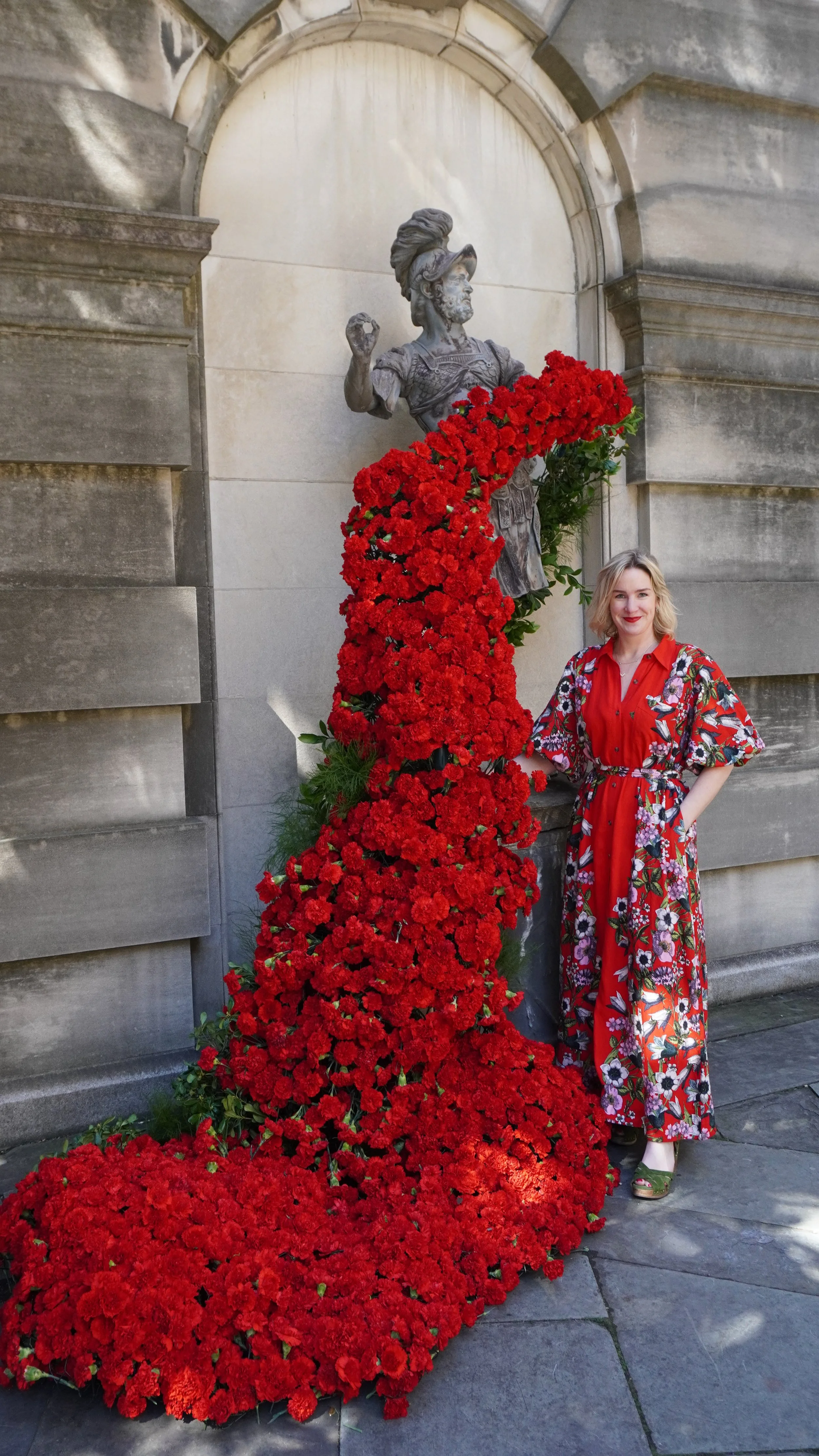 woman in red standing next to rose display