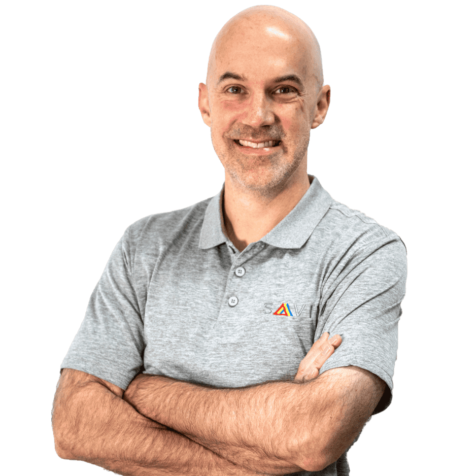 A smiling man with a shaved head and a gray polo shirt with a logo, arms crossed, looking at the camera.