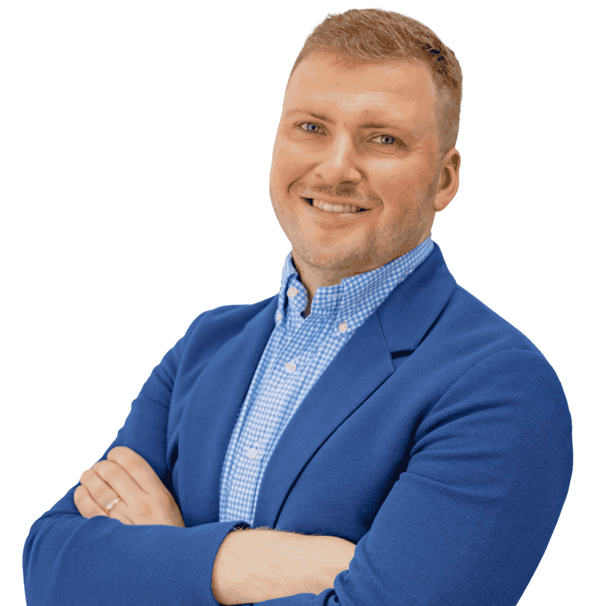 A man with light skin, short blonde hair, and blue eyes smiling with arms crossed, wearing a blue blazer and a blue and white checkered shirt, against a black background.