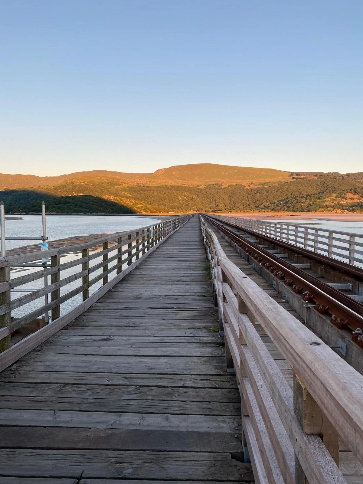 Walkway across Barmouth Bridge over the Mawddach Estuary at sunset