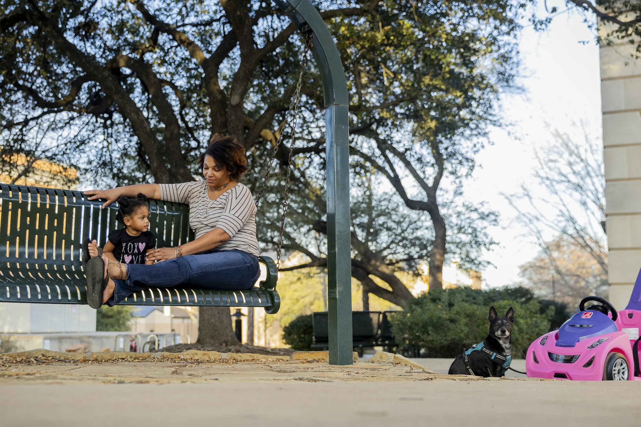 Besties for the Resties: Tarisa Banks, 33, swings with her 2-year-old daughter, Taylor, while their dog, Minnie, enjoys the sun near Sage Hall at UNT on March 3. Although she isn’t a student, Banks likes to take Taylor and Minnie on walks around camp