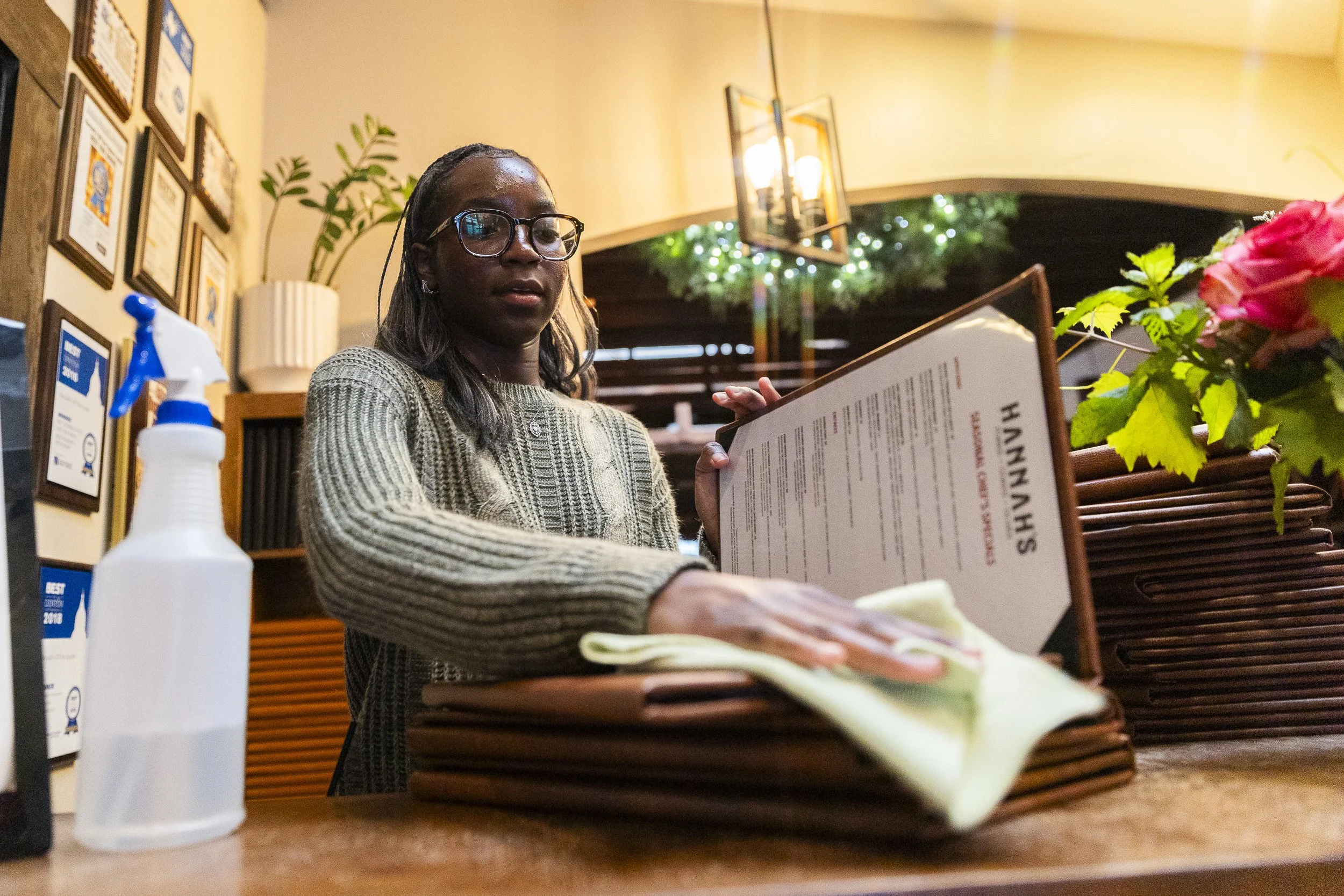 CLOSING TIME: Junior Lola Popoola ends her shift by cleaning the menus to prepare for rush hour at Hannah’s in Denton on April 29. Popoola has only been working at the restaurant for a little under a month.