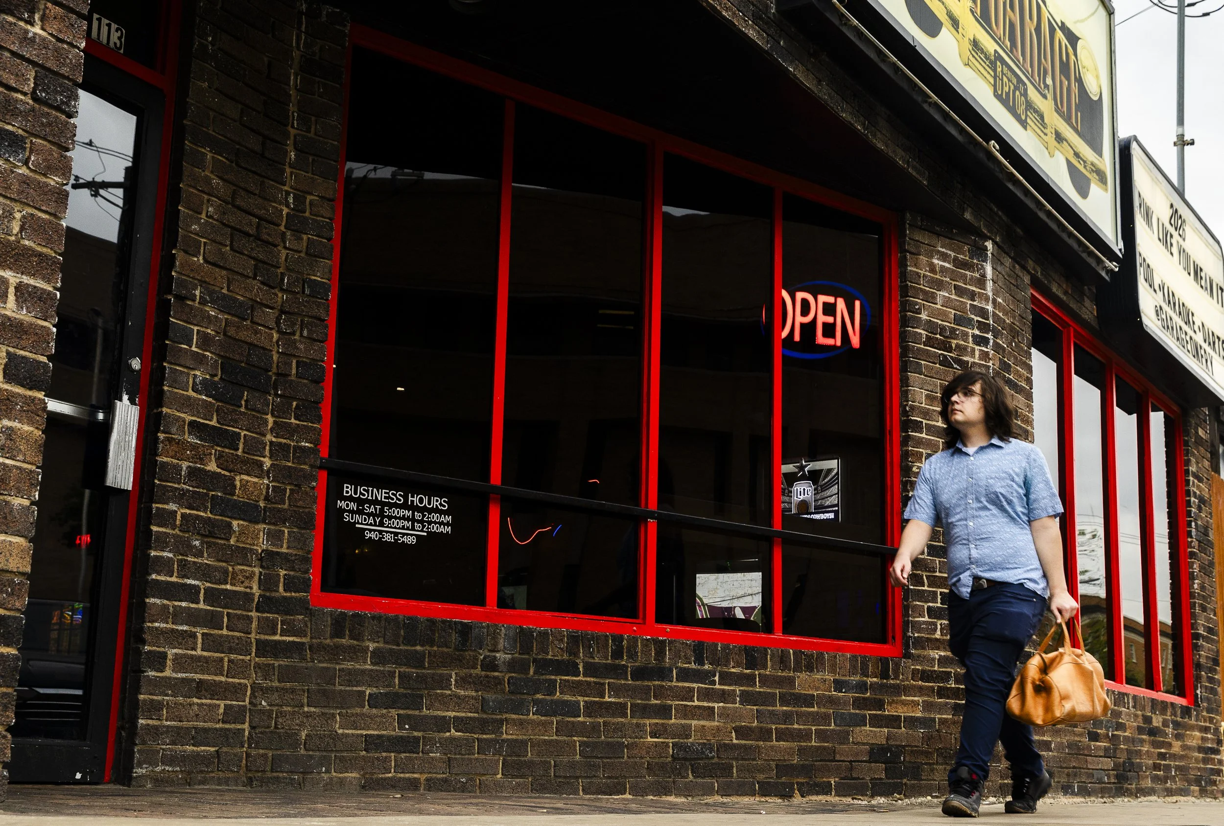 Follow the Red Brick Wall: Calvin Jeremy walks past The Garage on Fry Street in Denton on April 14. Fry Street is famously known for being the hotspot for UNT students to enjoy a night out without having to travel too far from campus.