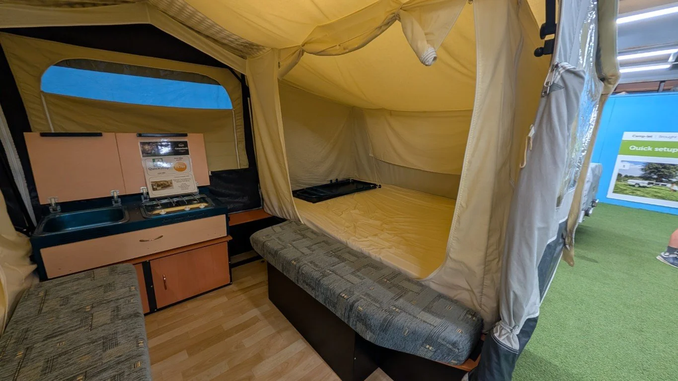 Interior of a pop-up camping tent with a small kitchenette and a fold-out sleeping area.
