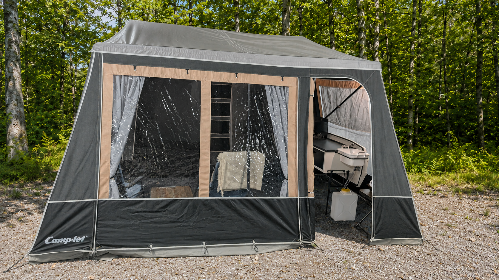 Tent set up outdoors in a wooded area, with a black and beige color scheme, featuring side mesh windows, an interior table with a towel, and a small sink with accessories inside.