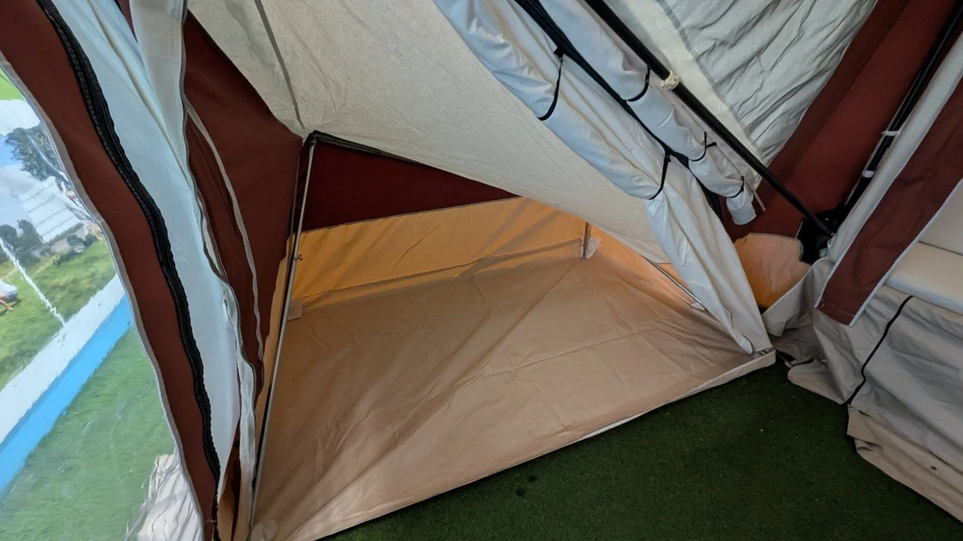 Inside view of a camping tent showing the open front flap, with a green grassy area visible outside.