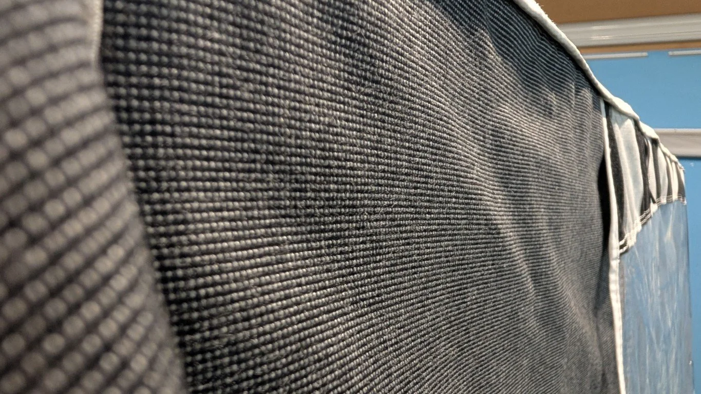 Close-up of a fabric surface with visible texture and a metallic zipper along the edge.