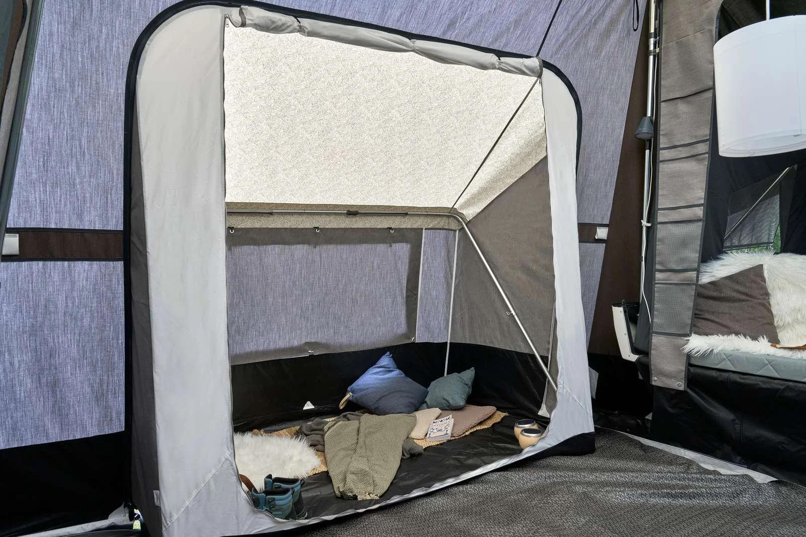 A white pop-up tent inside a room with a bed and pillows on the right side of the image.