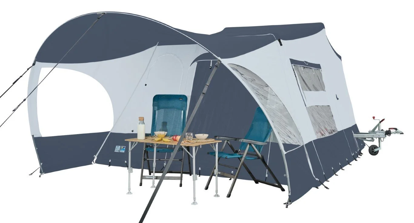 A Jamet Compact camping tent with an awning, two blue chairs, a small table with breakfast items, and a portable grill on a wheeled cart.
