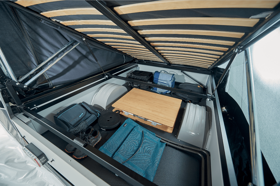 Indoor view of a compact Jamet storage compartment with luggage, a portable stove, and camping supplies.