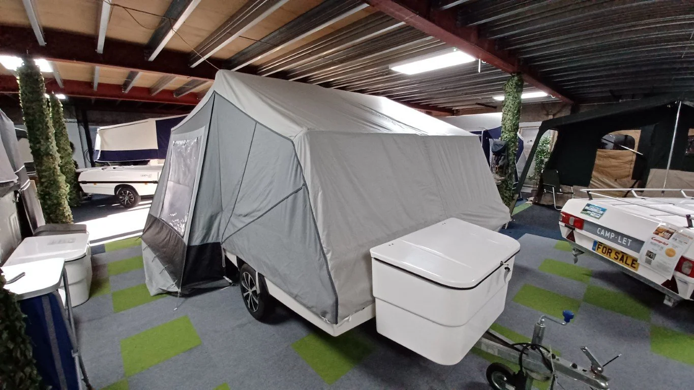An indoor display of camping and recreational vehicles, including a Camp-let Trailer Tent