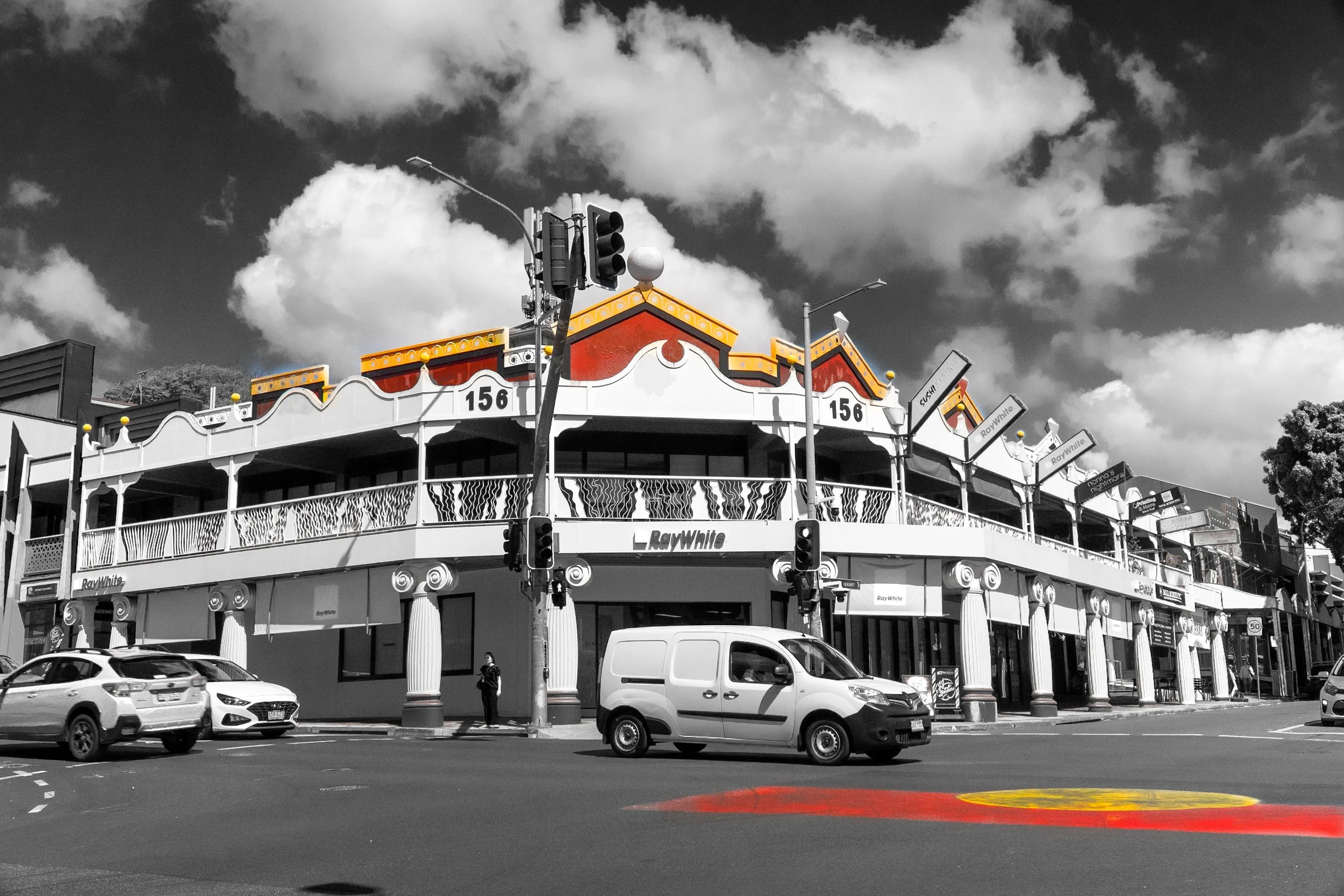 This photograph captures traditional architectural details through a selective colour approach. The warm orange rooftops stand out against the black-and-white buildings and dramatic sky, emphasising the structure's cultural character and visual contr