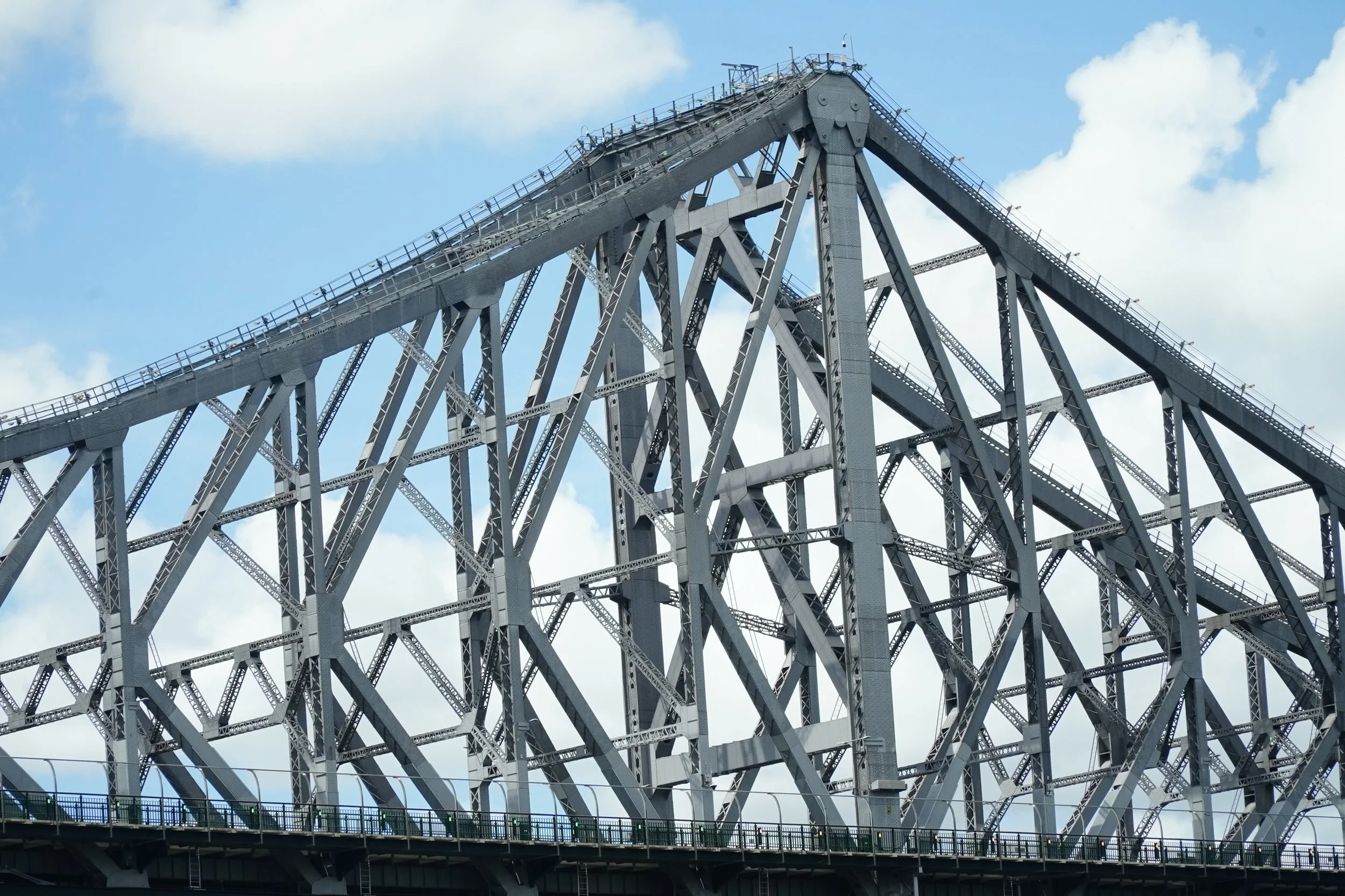 The picture depicts the remarkable steel construction of the Brisbane Story Bridge amidst a beautiful blue sky. The repeated patterns of beams and geometric forms in combination with the use of diagonals accentuate the industrial character of this ar