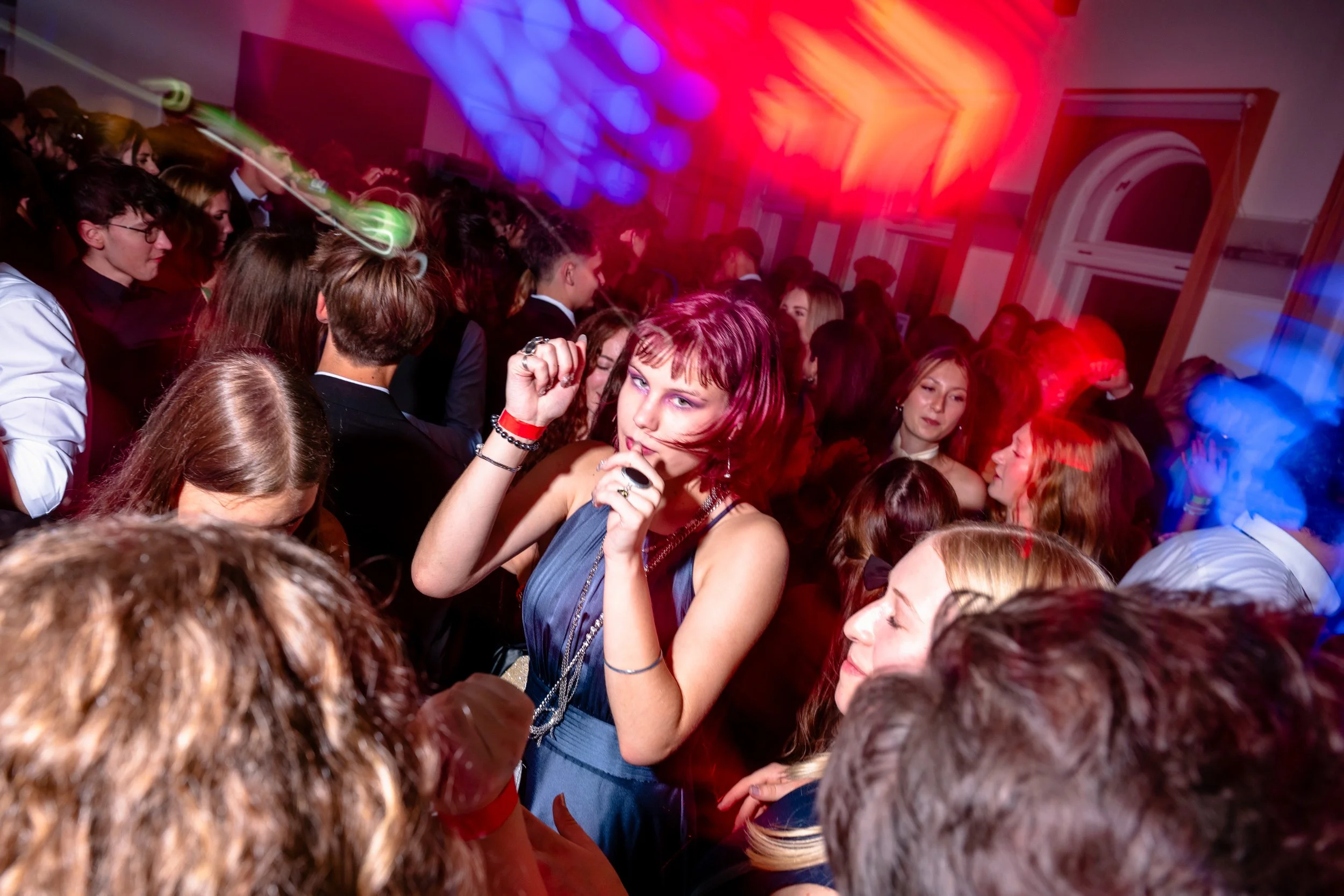 Menschen tanzen auf einer Party mit bunten Lichtern und einer lebhaften Atmosphäre.