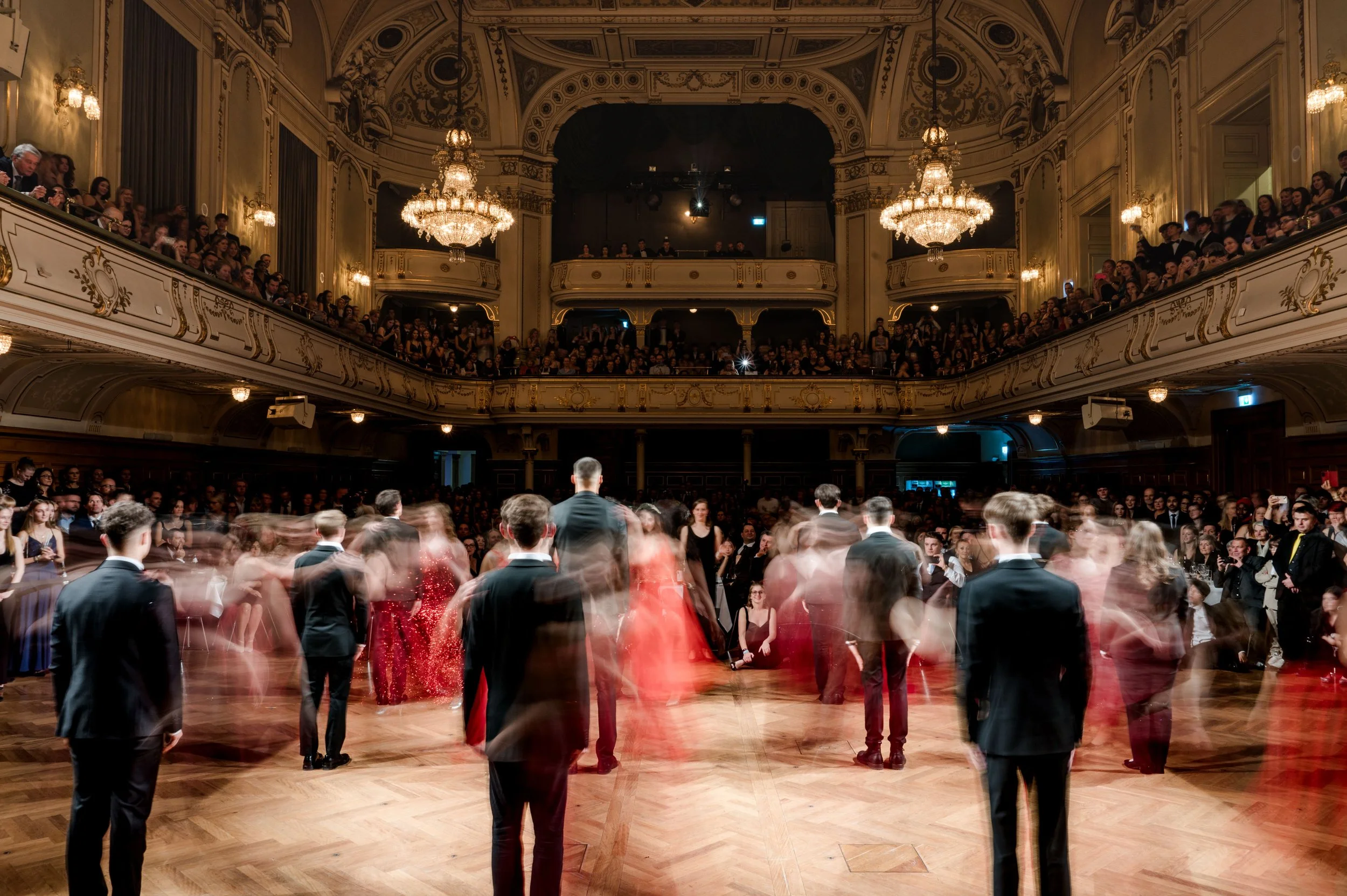 Tanzpaar im Ballsaal bei einem formellen Event, umliegende Gäste beobachten das Tanzen.
