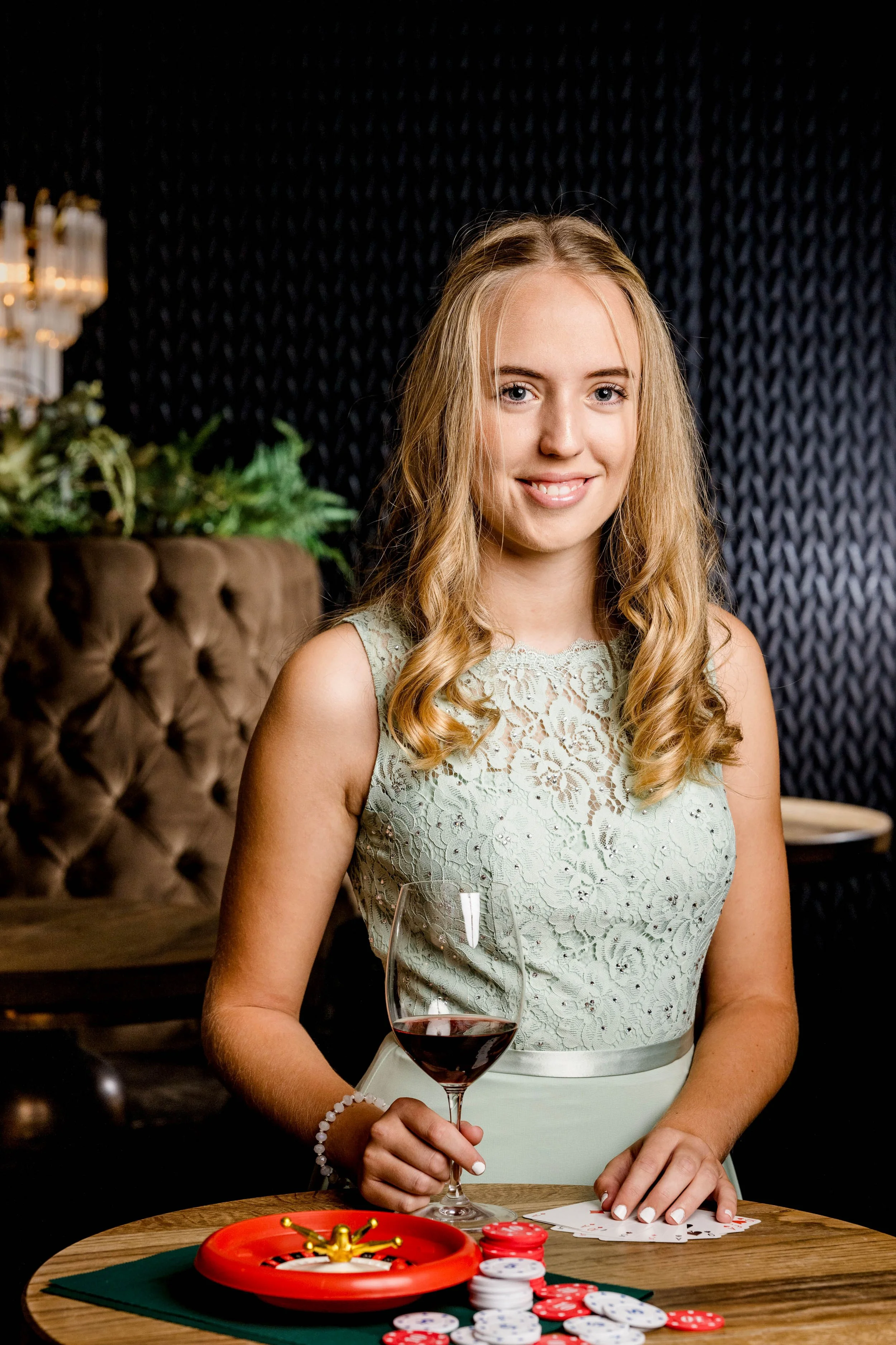 Junge Frau beim Poker mit Weinglas und Spielchips
