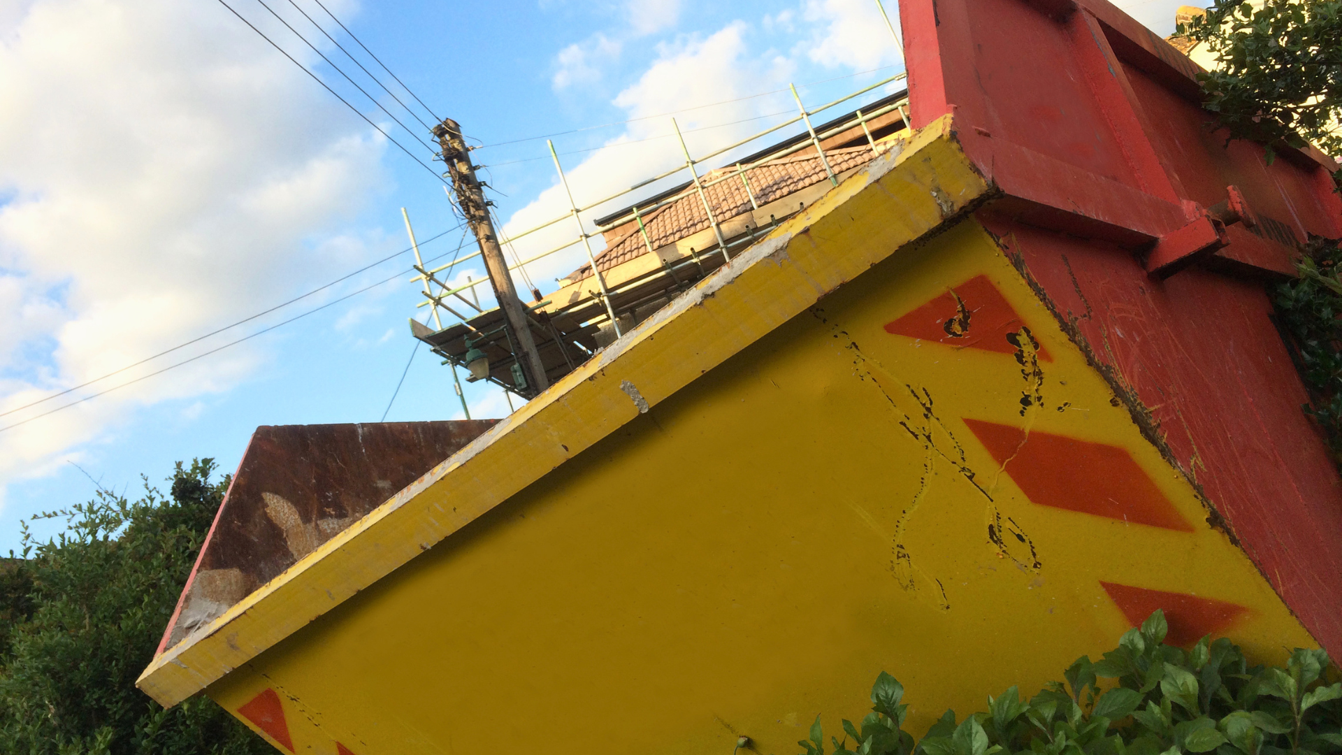 Image odf a skip with scaffolding and blue sky behind it