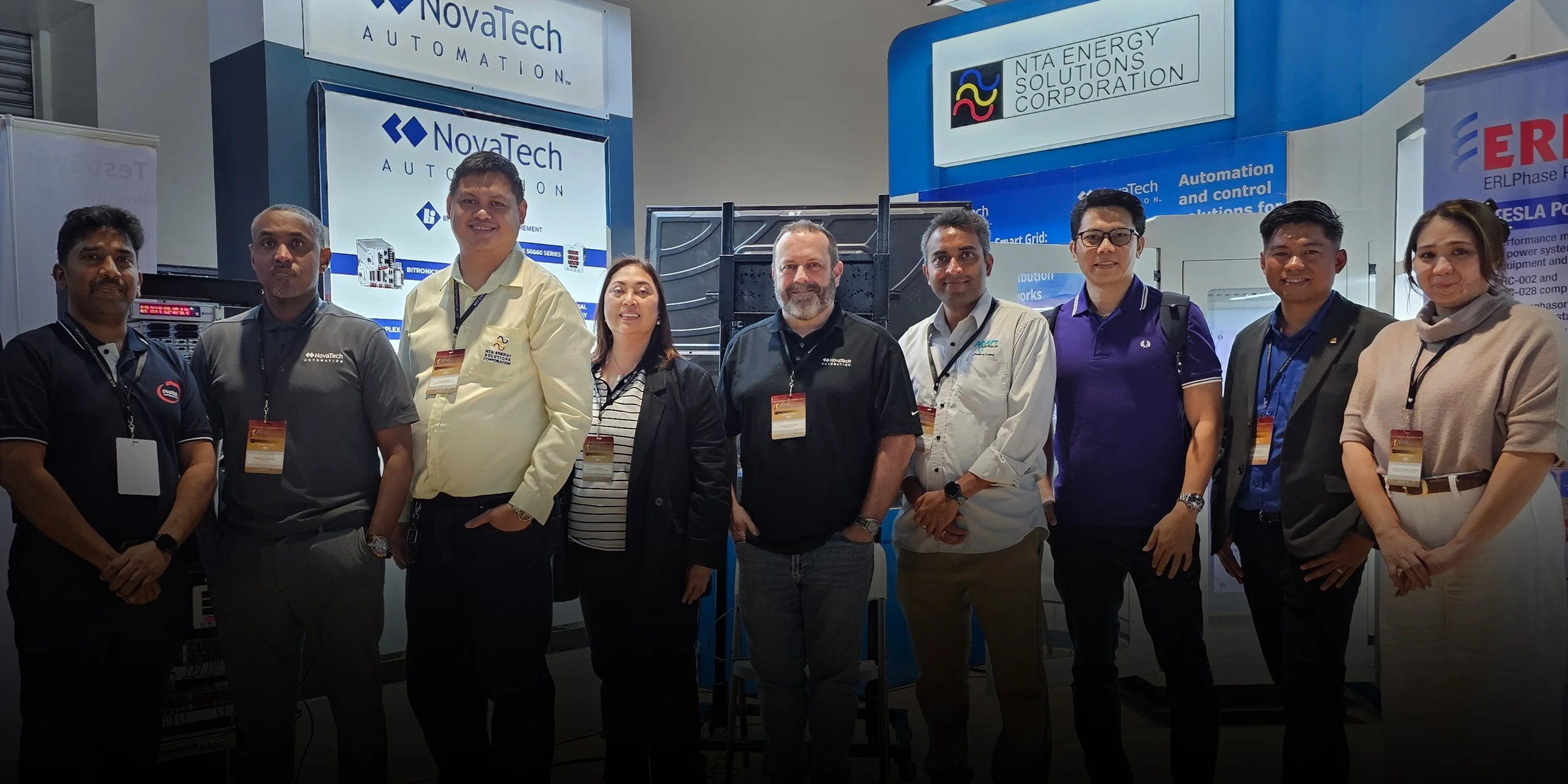 Group photo of people at a conference or event, standing on stage with a large screen in the background displaying various tech company logos.