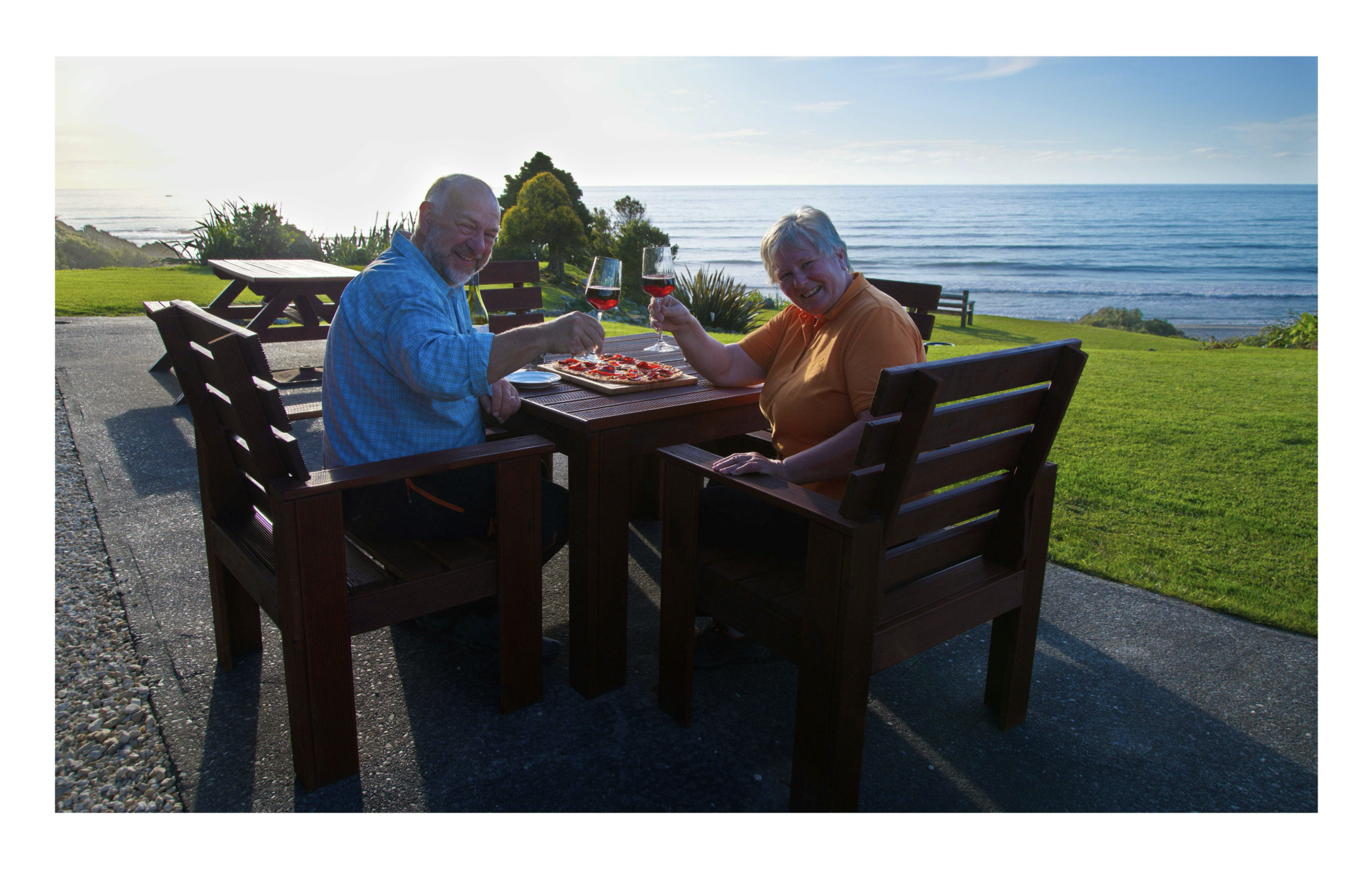 Guests enjoying pizza and wine and views to Tasman Sea from Breakers Boutique Accommodation.