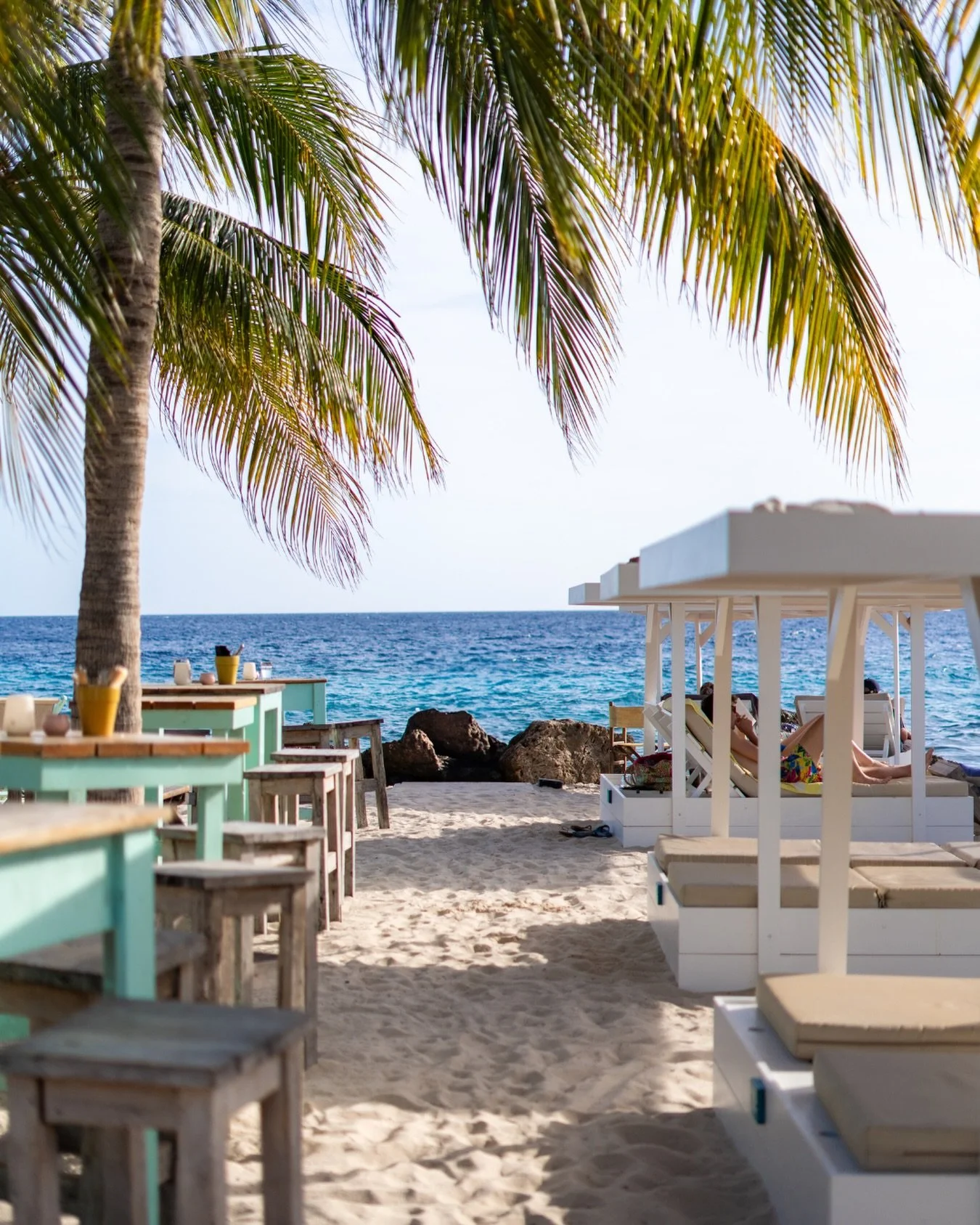 Palm trees overhead waving in the sea breeze, beach beds in the sand, and the sea waiting just a few steps away..

#beachsunset #oceanview #janthielbeach #curacao #beachlife