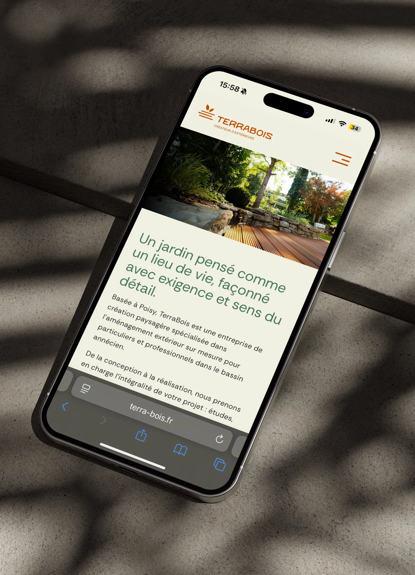 Capture d'écran d'un téléphone affichant le site web de TerraBois, une entreprise de création de jardins paysagers, avec une image de jardin en arrière-plan.
