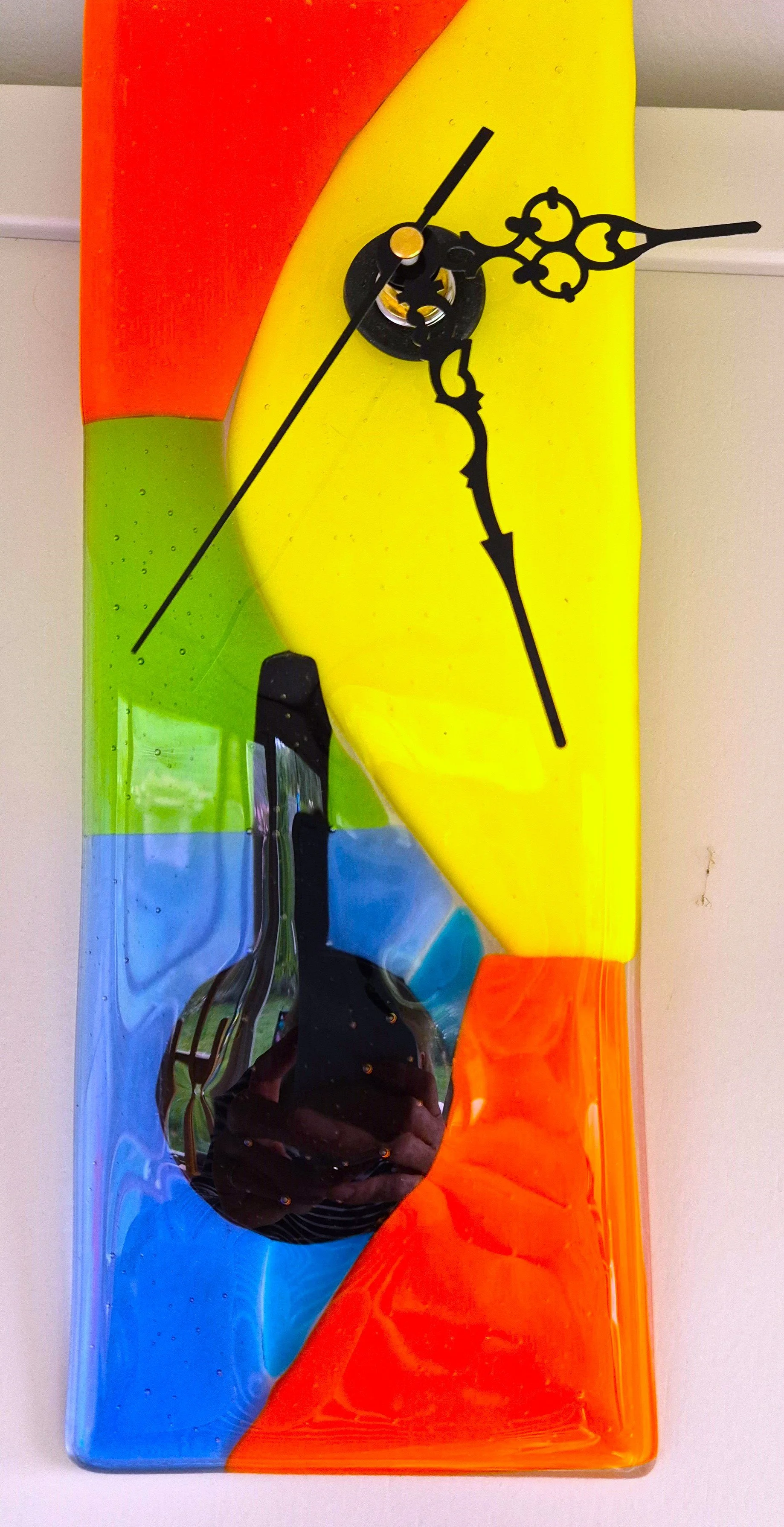 Colorful fish-shaped wall clock with black hands and rainbow background.