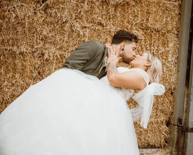 Bride and groom kissing in front of a haystack